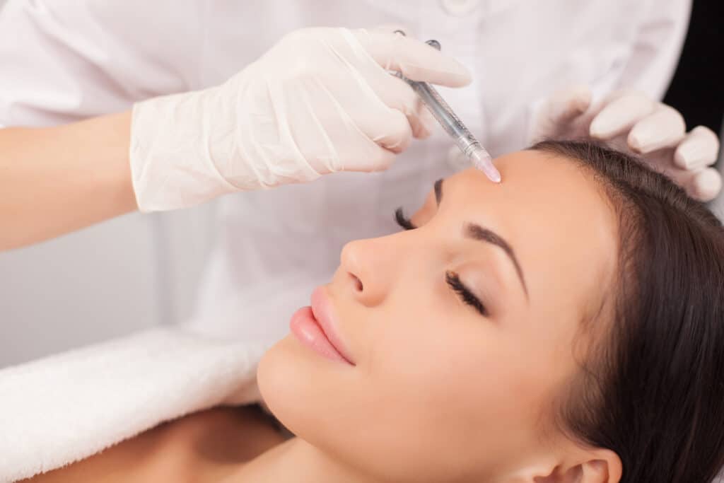 Woman smiles gently as her provider injects Dysport® in her forehead