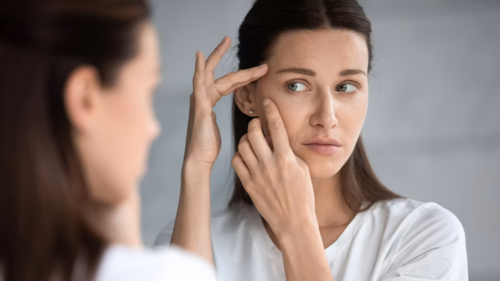 Woman checks for signs of adult acne in her bathroom mirror.