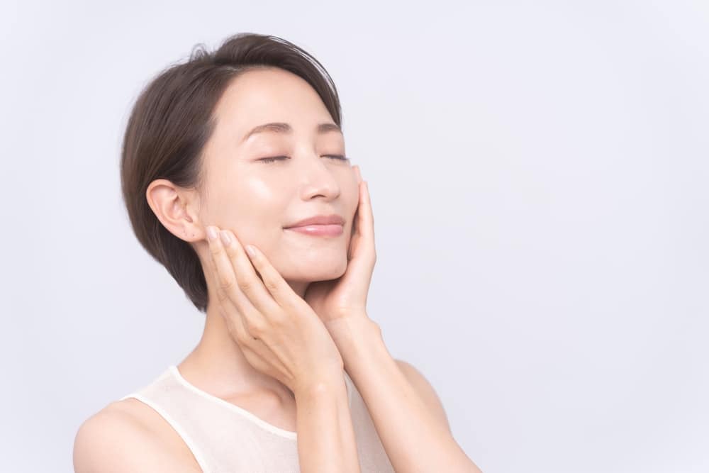 Woman rubs her cheek excited by the texture of her skin.